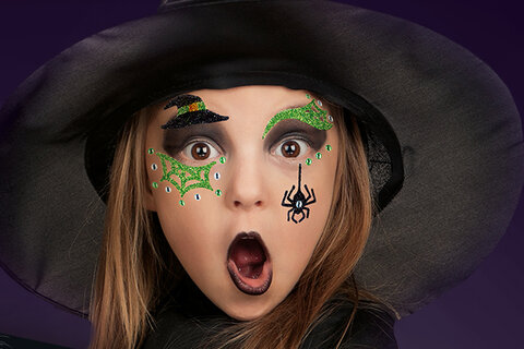 Meisje dat als heks verkleed is met Face Art-stickers.