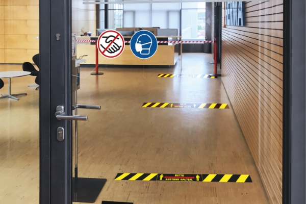 Deur met aanwijzingen en vloerstickers om afstand te houden