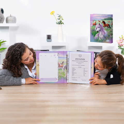 Twee meisjes zitten aan de tafel en bekijken een open schoolrapport in een kleurrijke map met een eenhoornmotief.