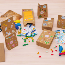 Kleurige cadeautasjes en knutselmaterialen op een tafel, waaronder stickers, ballonnen, scharen en snoepjes.