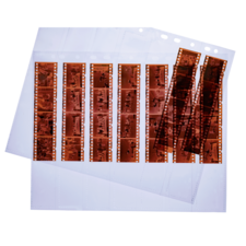 Filmnegative in Klarsichthüllen, angeordnet in Reihen, mit verschiedenen Motiven und Bildern. Einige Negative sind lose daneben.