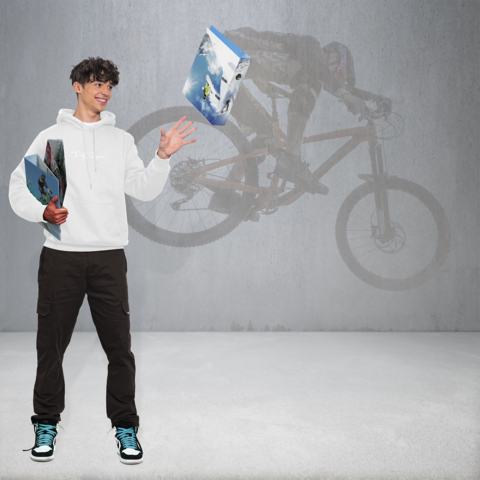 Ein junger Mann in einem weißen Hoodie steht mit zwei Boxen in der Hand, während im Hintergrund ein Radfahrer auf einem Mountainbike zu sehen ist.