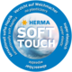 Rundes Logo von HERMA mit dem Text "SOFT TOUCH", der auf weiche Haptik, Elastizität und den Verzicht auf Weichmacher hinweist.