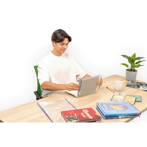 Ein junger Mann sitzt an einem Tisch, nutzt ein Tablet und hat mehrere Bücher sowie Schreibmaterialien um sich herum. Eine Pflanze ist ebenfalls sichtbar.