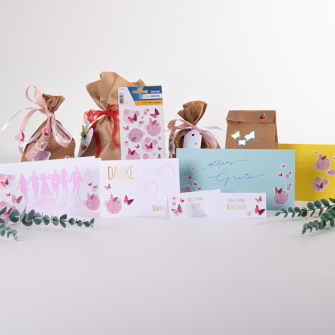 Geschenktassen en kaarten in verschillende kleuren en ontwerpen, waaronder een 'Dankjewel'-kaart en een 'Gefeliciteerd'-kaart, versierd met vlinders.
