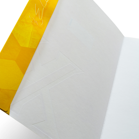 Gelbes Notizbuch mit einem geometrischen Muster auf dem Deckel, innen leer und unbeschrieben.