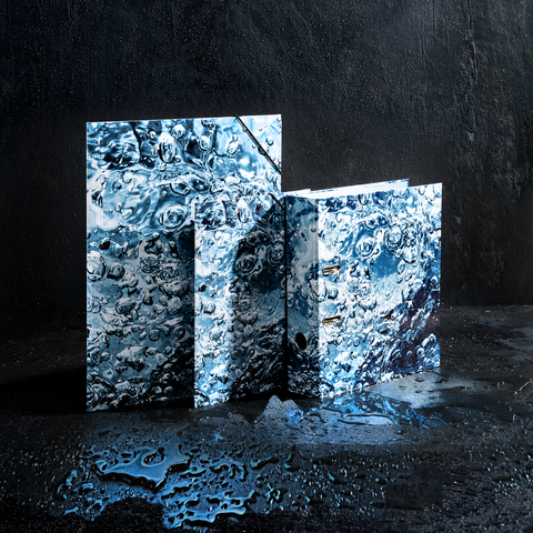 Wasserbedeckte Ordner und Notizbücher in verschiedenen Größen, die auf einer dunklen Oberfläche stehen, mit reflektierenden Wassertropfen.