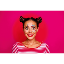 Frau mit buntem Gesichtsschmuck und roten Lippen, trägt ein gestreiftes Oberteil und hat zwei Duttfrisuren, vor einem pinken Hintergrund.