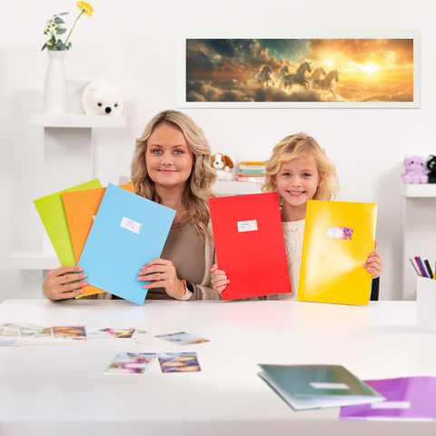 Een vrouw en een kind zitten aan een tafel met kleurrijke mappen in hun handen. Op de tafel liggen foto's en op de achtergrond is een afbeelding van paarden te zien.