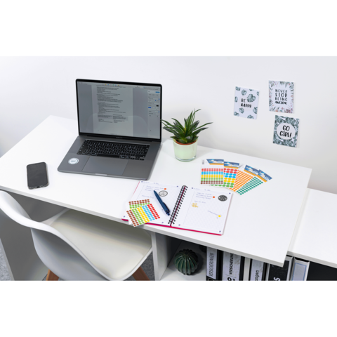 Ein Schreibtisch mit einem Laptop, einer Pflanze, Notizbuch und bunten Karten. An der Wand hängen inspirierende Zitate.