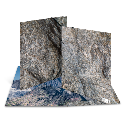 Eine geöffnete Mappe mit Felszeichnungen und einer Landschaftsaufnahme im Hintergrund, die Gebirgszüge zeigt.