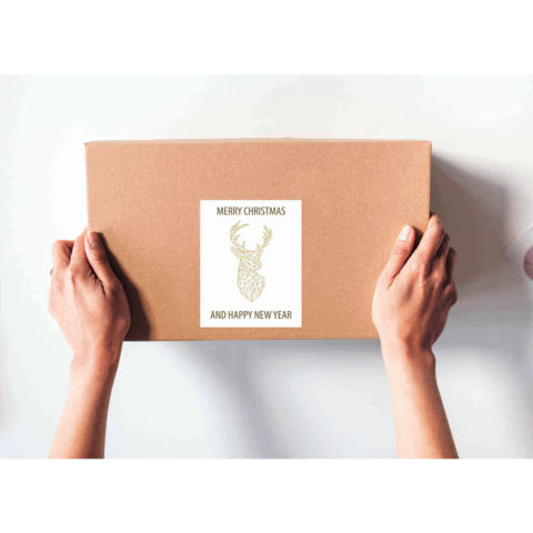 Eine Person hält ein braunes Paket mit einem Aufkleber, der "Frohe Weihnachten und ein gutes neues Jahr" zeigt, dekoriert mit einem Rentier.