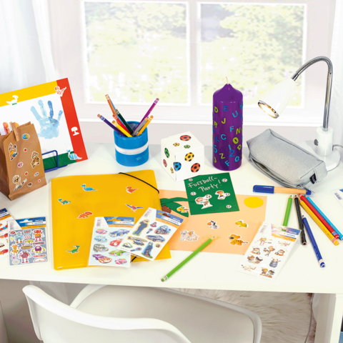 Fel gekleurde bureau met knutselmaterialen, waaronder stiften, stickers, een map en een lamp.