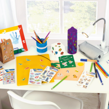 Fel gekleurde bureau met knutselmaterialen, waaronder stiften, stickers, een map en een lamp.
