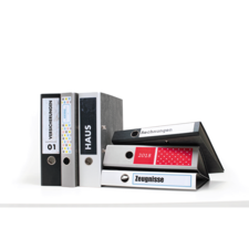 Eine Gruppe von Ordnern in verschiedenen Farben, beschriftet mit "Versicherungen", "Haus", "Rechnungen" und "Zeugnissen".